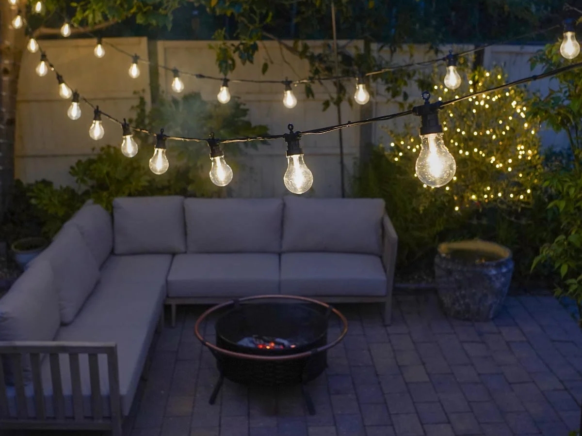 Nếu bạn sở hữu một hố lửa ở ngoài sân vườn, thì tốt nhất là nên trang trí thêm đèn dây trên cao để tạo ra hiệu ứng như những ngôi sao trên bầu trời tối