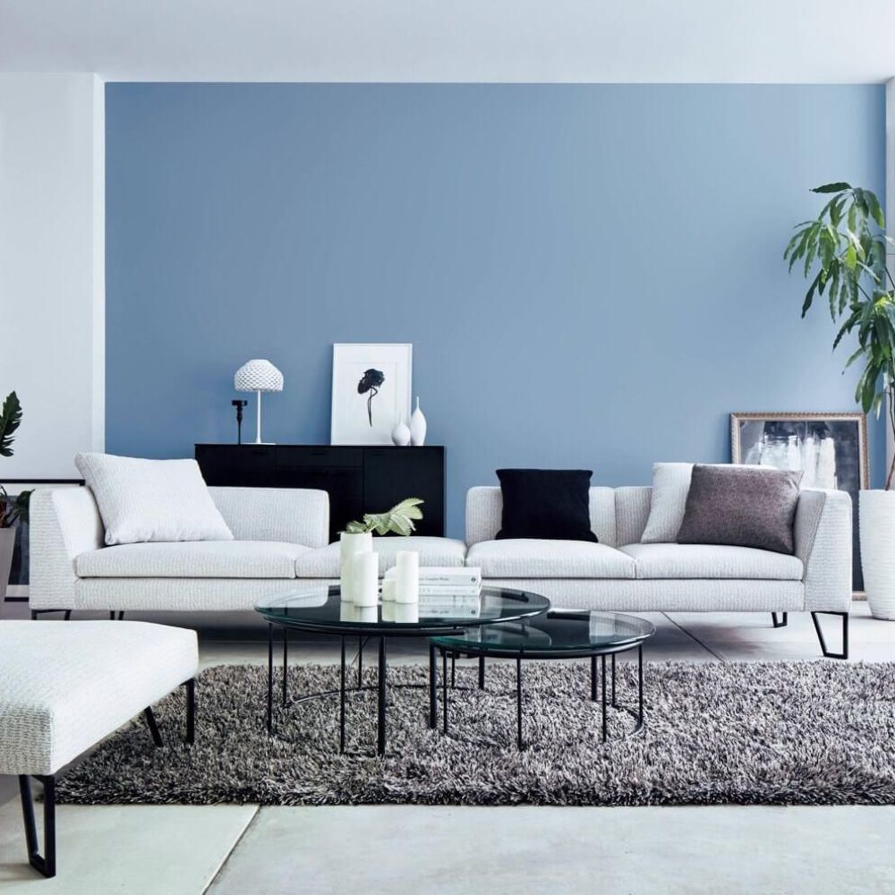 Ph&ograve;ng kh&aacute;ch nh&agrave; ống ấn tượng với tường xanh dương nổi bật kết hợp bộ sofa trắng v&agrave; thảm x&aacute;m l&ocirc;ng d&agrave;i